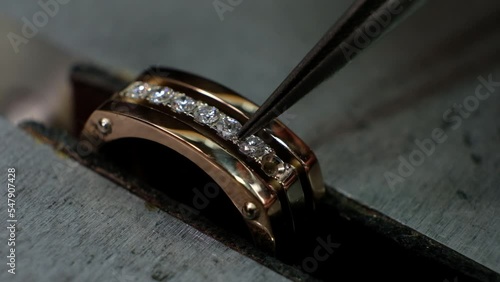Craft jewelery making. Goldsmith putting the diamond on the ring. Macro shot