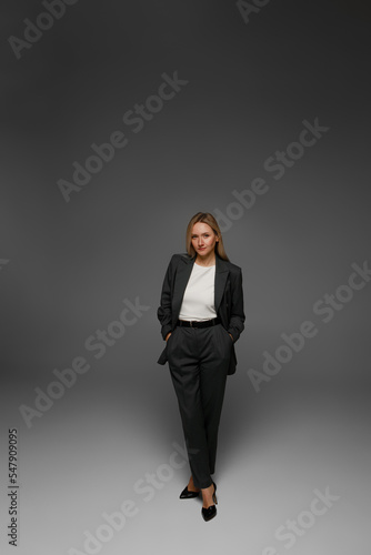 middle aged woman in office suit in studio with gray background