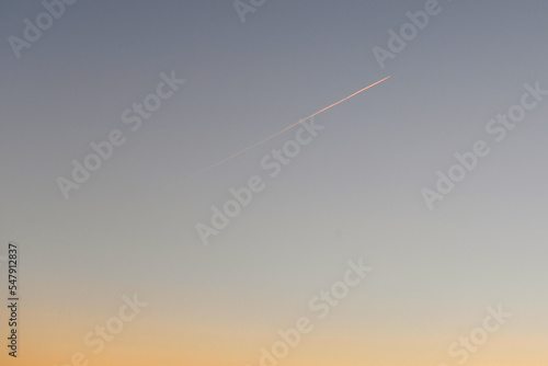 夕暮れの空に一本の飛行機雲