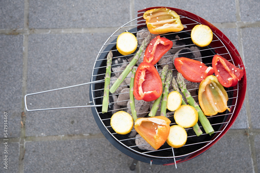 barbecue of colorful raw vegetables on a grill on blue shabby boards, vegetarian