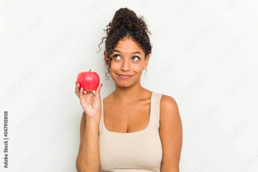 Young brazilian woman holding a red apple isolated dreaming of achieving goals and purposes Young brazilian woman holding a red apple isolated dreaming of achieving goals and purposes