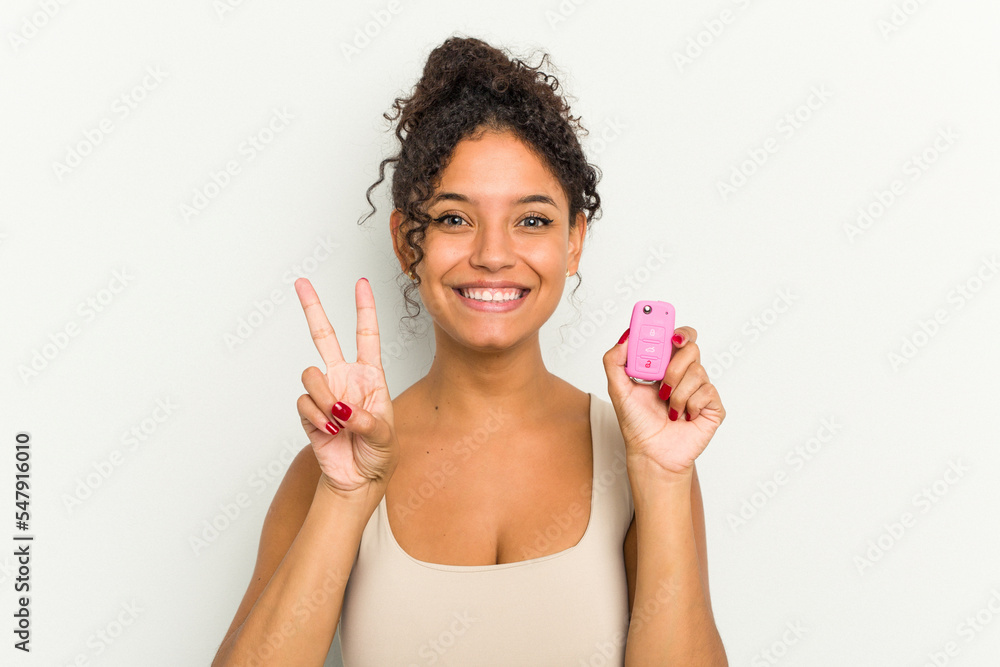 Young brazilian woman holding home keys isolated showing number two with fingers. Young brazilian woman holding home keys isolated showing number two with fingers.