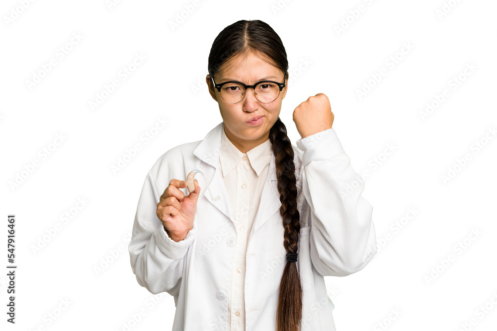 Young asian otorhinolaryngologist woman holding a hearing aid isolated showing fist to camera, aggressive facial expression. Young asian otorhinolaryngologist woman holding a hearing aid isolated showing fist to camera, aggressive facial expression.