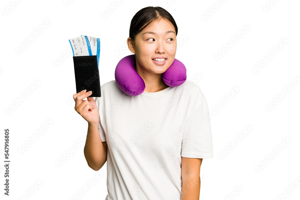 Young asian woman with inflatable travel pillow on her neck holding passport isolated looks aside smiling, cheerful and pleasant. Young asian woman with inflatable travel pillow on her neck holding passport isolated looks aside smiling, cheerful and pleasant.