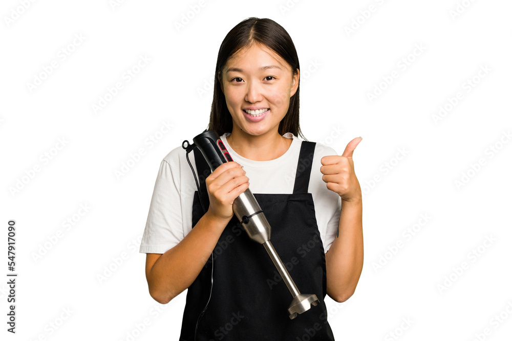 Young asian cook woman holding a blender isolated smiling and raising thumb up Young asian cook woman holding a blender isolated smiling and raising thumb up