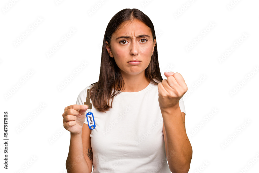 Young caucasian woman holding a home keys isolated showing fist to camera, aggressive facial expression. Young caucasian woman holding a home keys isolated showing fist to camera, aggressive facial expression.