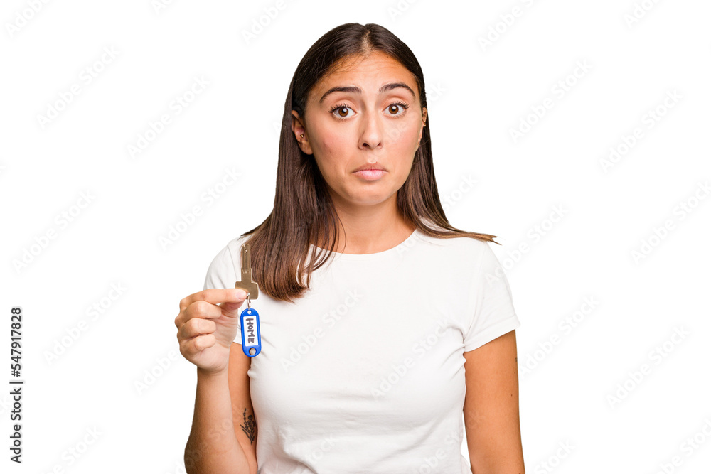 Young caucasian woman holding a home keys isolated shrugs shoulders and open eyes confused. Young caucasian woman holding a home keys isolated shrugs shoulders and open eyes confused.