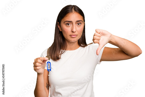 Young caucasian woman holding a home keys isolated showing a dislike gesture, thumbs down. Disagreement concept.
