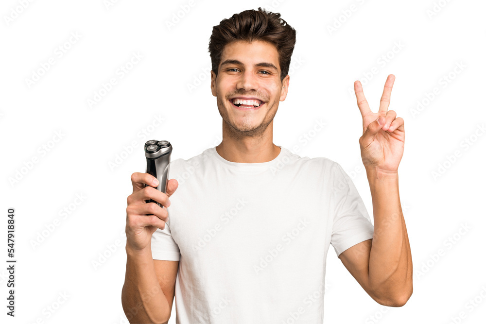 Young caucasian man holding a razor isolated joyful and carefree showing a peace symbol with fingers. Young caucasian man holding a razor isolated joyful and carefree showing a peace symbol with fingers.
