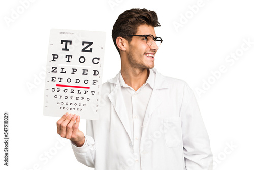 Young caucasian oculist man isolated looks aside smiling, cheerful and pleasant.