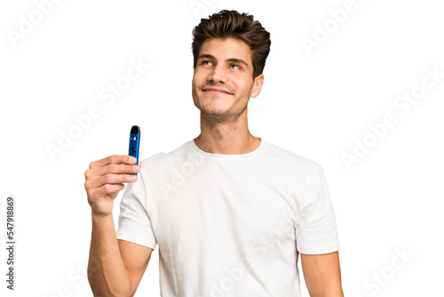 Young caucasian man holding an electronic cigarette isolated dreaming of achieving goals and purposes