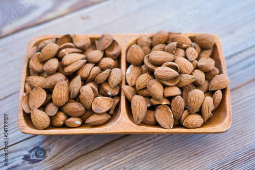 Almonds nuts on wooden bowl on table background , top view  almond © ACHILLEFS