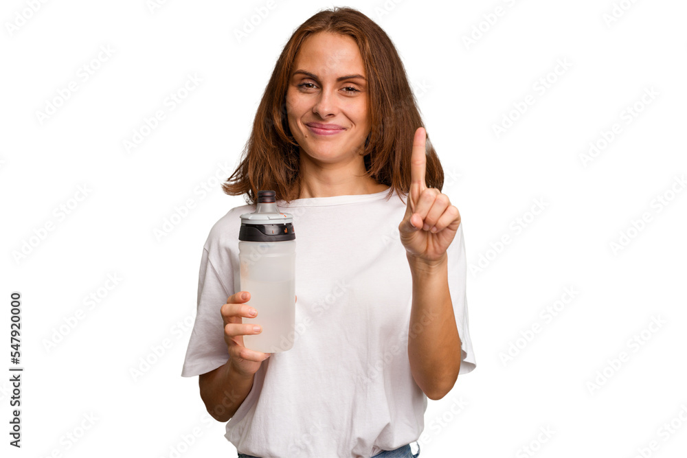 Young caucasian sport woman holding a bottle of water isolated showing number one with finger. Young caucasian sport woman holding a bottle of water isolated showing number one with finger.