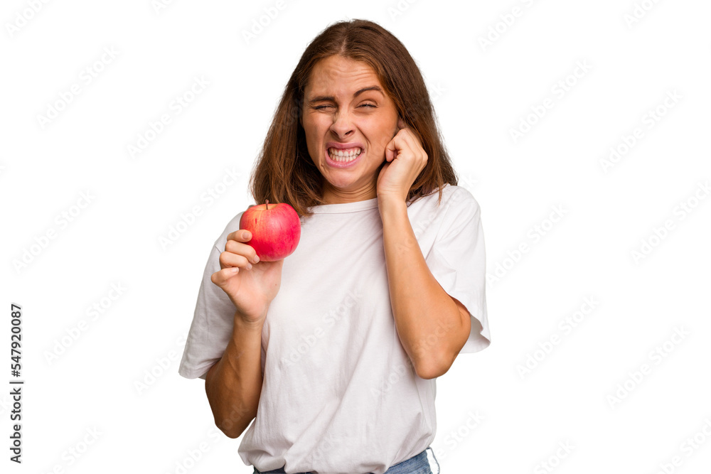 Young caucasian woman holding a red apple isolated covering ears with hands. Young caucasian woman holding a red apple isolated covering ears with hands.