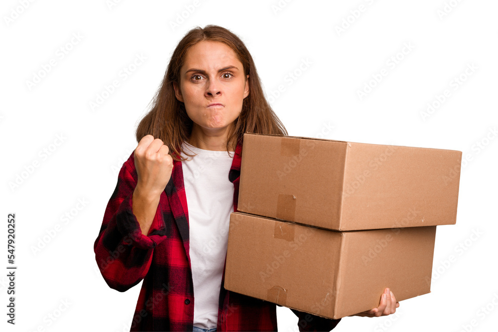 Young caucasian woman moving while picking up a box full of things isolated showing fist to camera, aggressive facial expression. Young caucasian woman moving while picking up a box full of things isolated showing fist to camera, aggressive facial expression.