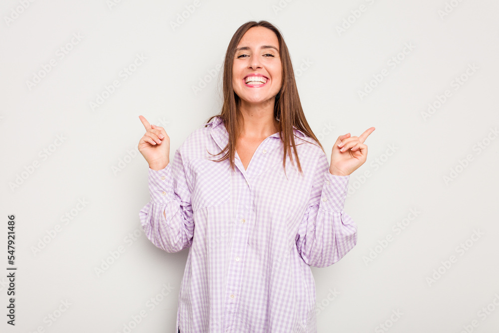 Young caucasian cute woman isolated on white background pointing to different copy spaces, choosing one of them, showing with finger.