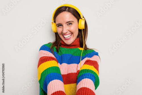 Young caucasian woman listening to music with headphones isolated on white background © Asier