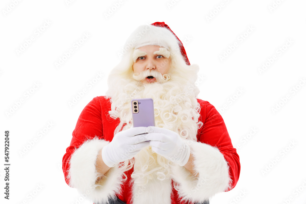 Santa Claus is surprised with a smartphone in his hands on a white background. Santa Claus is surprised with a smartphone in his hands on a white background.