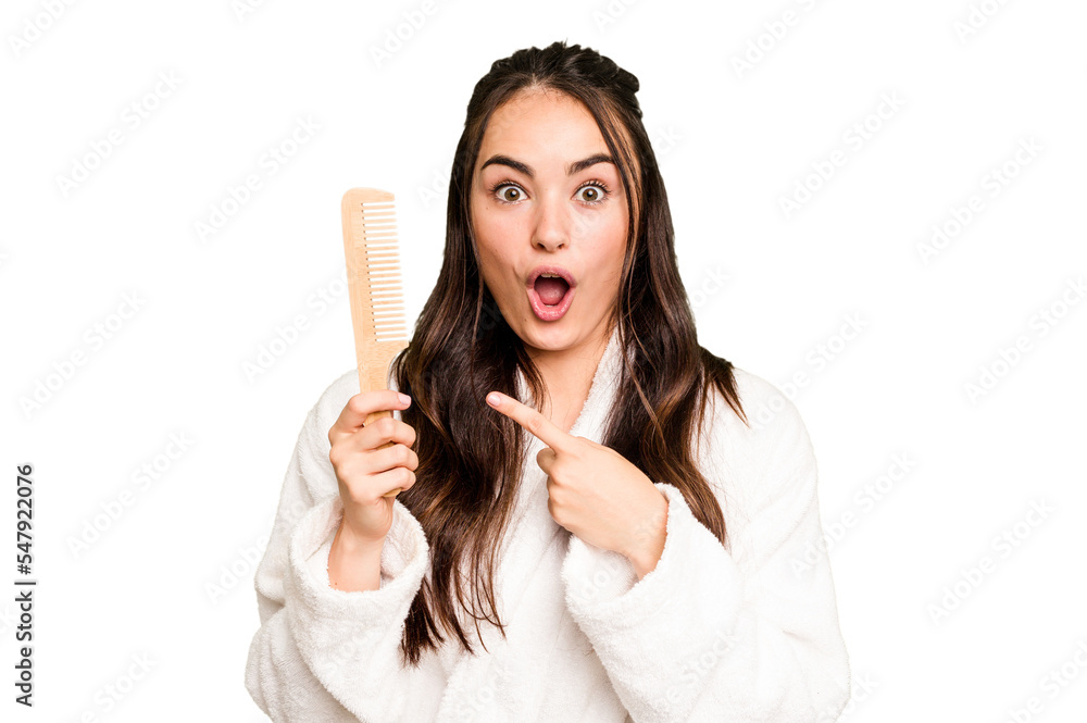 Young caucasian woman holding a hairbrush isolated on green chroma background pointing to the side Young caucasian woman holding a hairbrush isolated on green chroma background pointing to the side