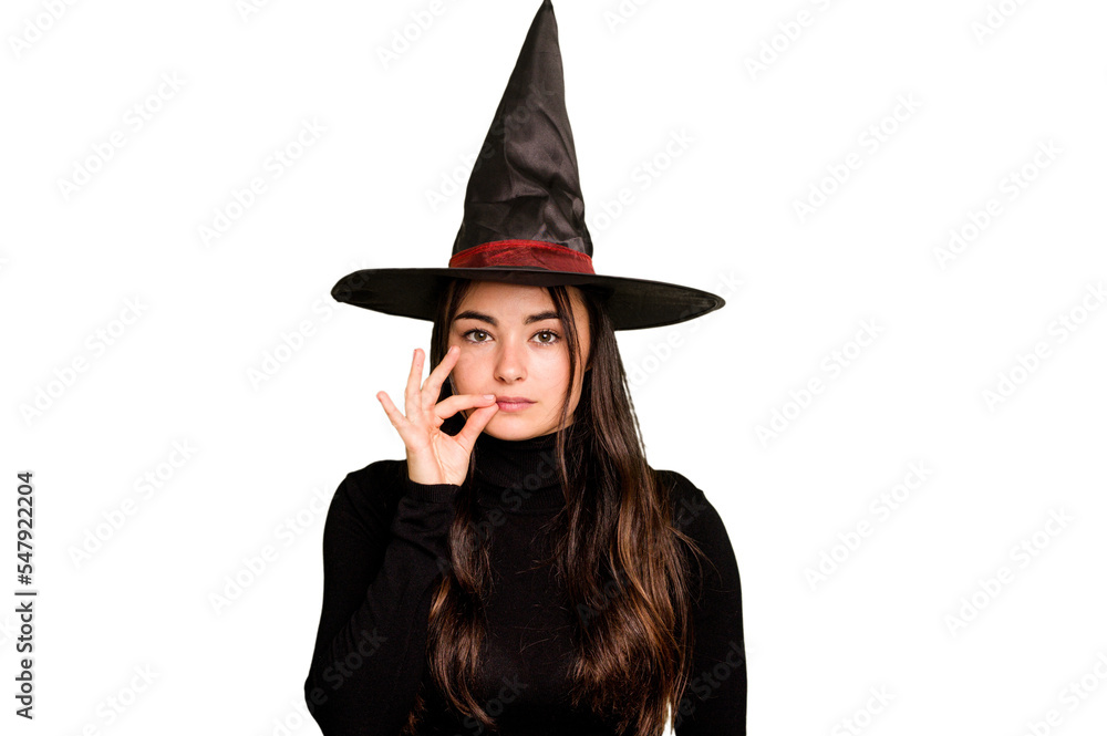 Young caucasian woman dressed as a witch isolated on green chroma background with fingers on lips keeping a secret. Young caucasian woman dressed as a witch isolated on green chroma background with fingers on lips keeping a secret.