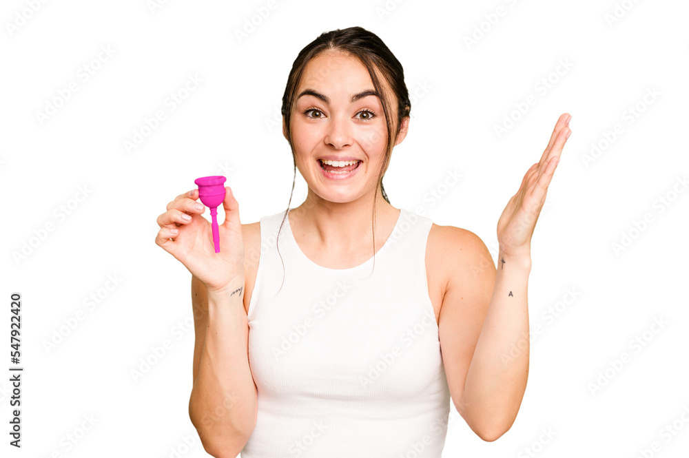 Young caucasian woman holding menstrual cup isolated on green chroma background receiving a pleasant surprise, excited and raising hands. Young caucasian woman holding menstrual cup isolated on green chroma background receiving a pleasant surprise, excited and raising hands.