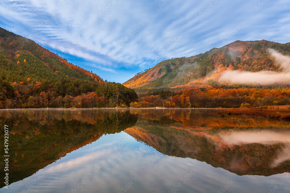 秋の大滝川ダムに映る紅葉の山々と青空,