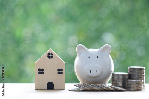 Finance, Model house with piggy bank and stack of coins money on natural green background,Business investment and real estate concept