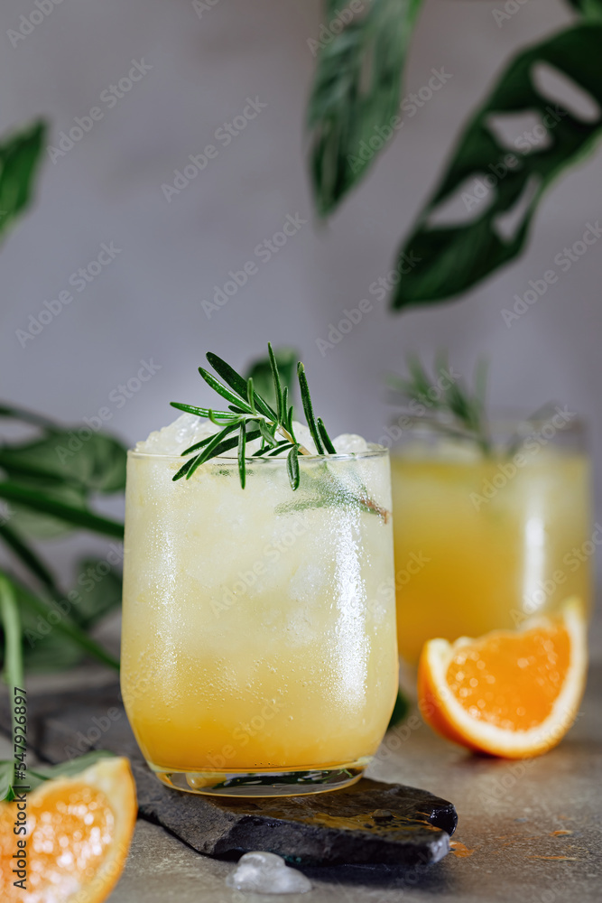 Cold summer refreshing orange and ice drink with a sprig of rosemary Cold summer refreshing orange and ice drink with a sprig of rosemary