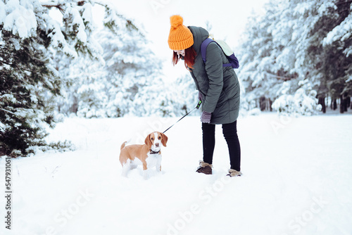 Woman with red hair playing with her dog in a winter forest