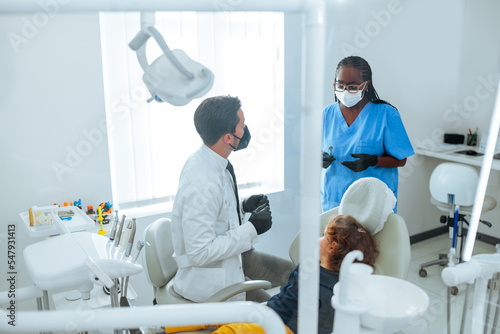 Dentist assistant helping doctor in office.