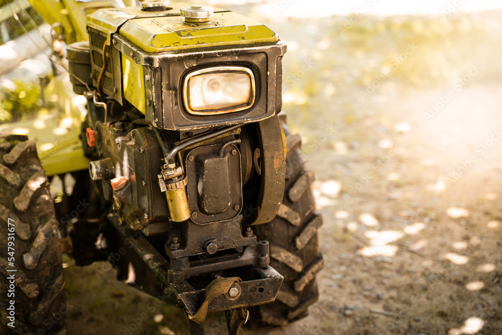 Walk-behind tractor with headlight close-up on a blurred background. Farming mini tractor Walk-behind tractor with headlight close-up on a blurred background. Farming mini tractor