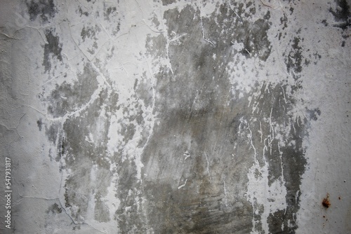 A weathered concrete wall with cracks and peeling paint, showing signs of age and decay.