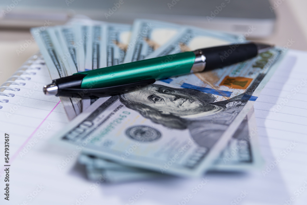 pen on a fan of U.S. dollars, make calculations, deductions, and pen on a fan of U.S. dollars, make calculations, deductions, and