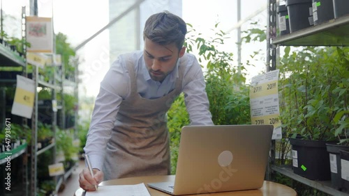 owner of a flower shop making notes on the clipboard.