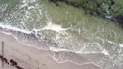 Low drone view of waves rolling onto Baltic Sea beach of Graal-Müritz, Mecklenburg-Western Pomerania, Germany