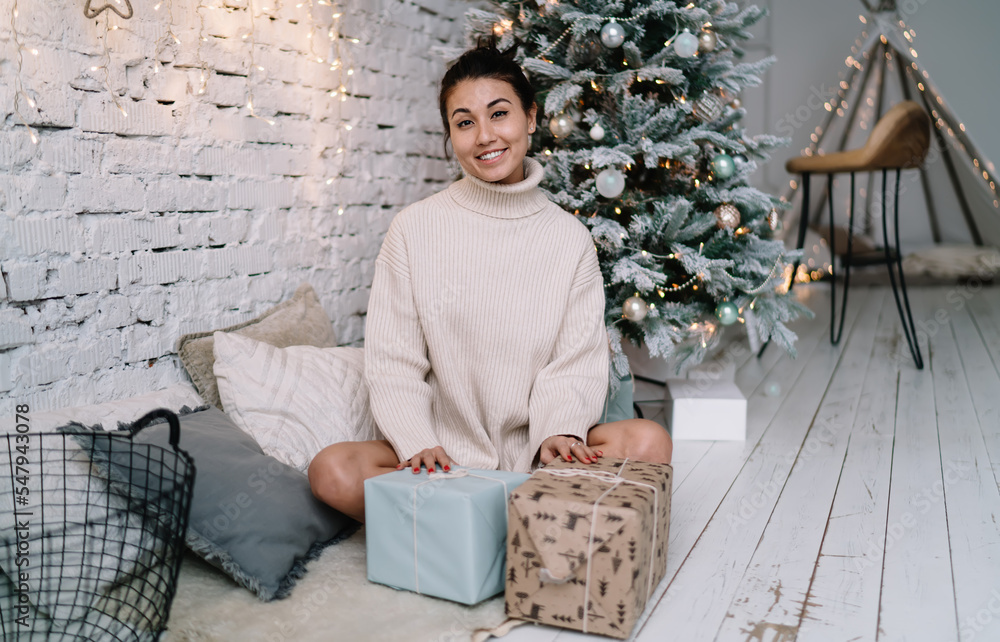 Asian woman with gifts near Christmas tree at home Asian woman with gifts near Christmas tree at home