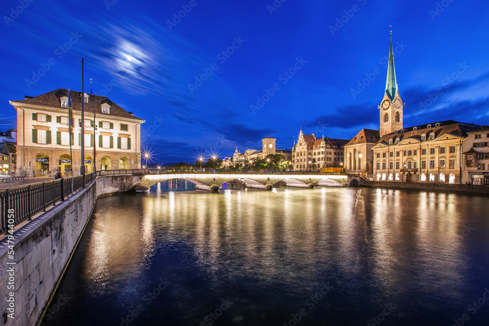 Naklejka premium Stadt Zürich in der Schweiz bei Nacht mit dem Fluss Limmat im Vordergrund.