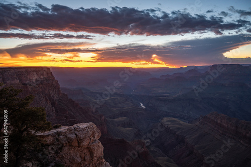 Desert landscape of the famous Grand Canyon at dusk, there are clouds and the orange sky