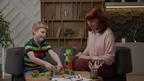 Kid building with wooden blocks sitting at therapist office. Awareness of children's mental health and education.