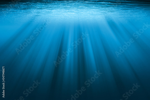Underwater background with copy space. Blue water with sunbeams.