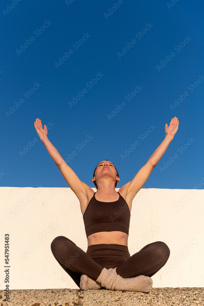 Obraz premium Sporty woman with raised arms to the sky, enjoying the freedom of the outdoors and sunshine.
