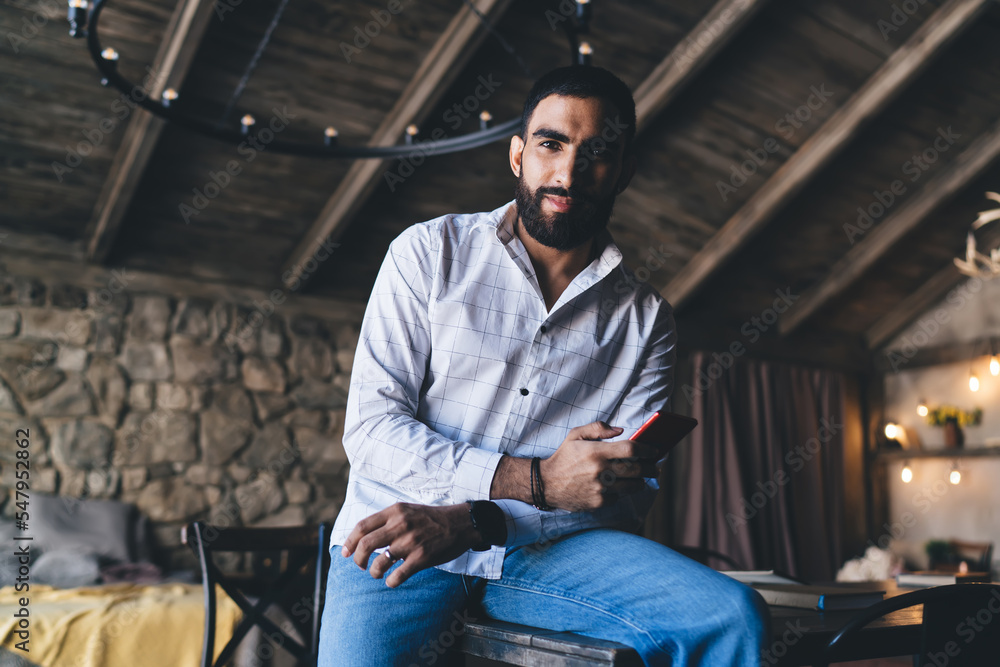 Ethnic man browsing smartphone in contemporary apartment