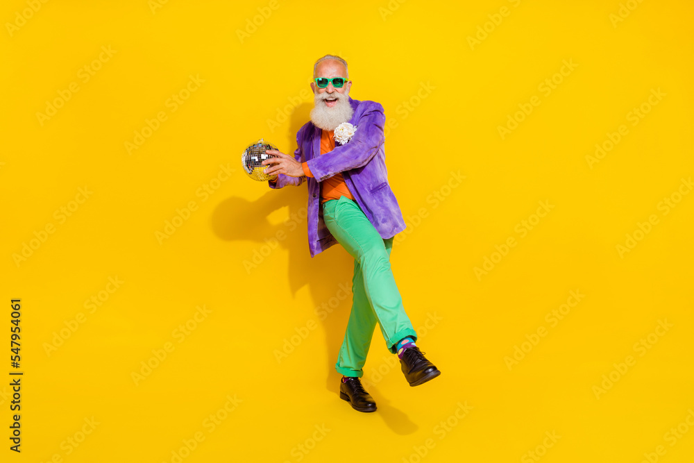 Full body portrait of excited crazy granddad arms hold disco ball dancing isolated on yellow color background Full body portrait of excited crazy granddad arms hold disco ball dancing isolated on yellow color background