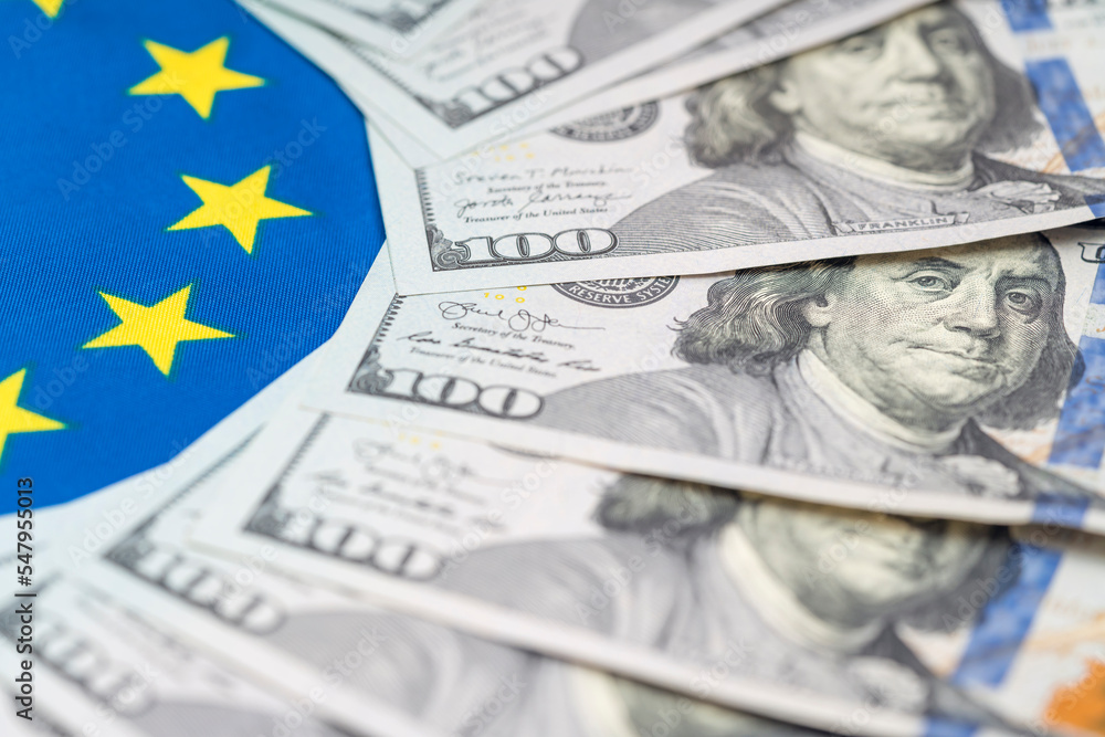 100 dollars bills against background of EU flag. Financial condition of residents of European Union, taxes, loans, mortgages. State debt of country 100 dollars bills against background of EU flag. Financial condition of residents of European Union, taxes, loans, mortgages. State debt of country