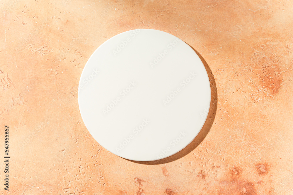 Empty white circle mockup podium for product presentation on a sandy textured background with hard light. Trendy design flat lay with copy space. Top view.