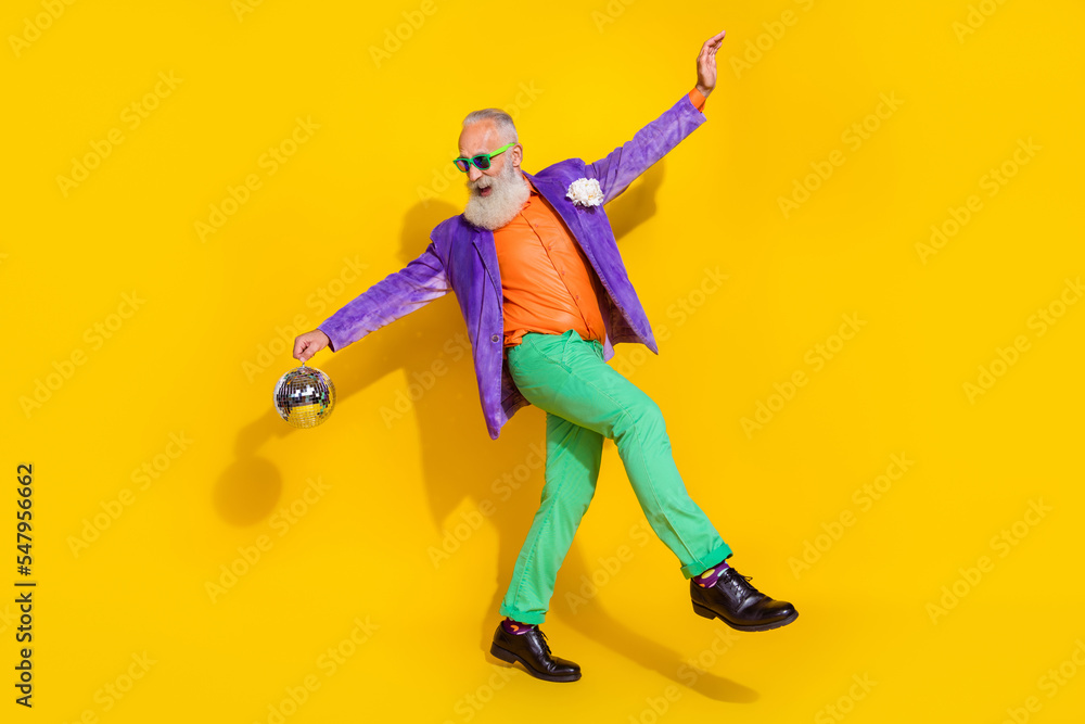 Full length photo of charming positive guy dressed violet velvet jacket having fun holding disco ball hands sides isolated yellow color background