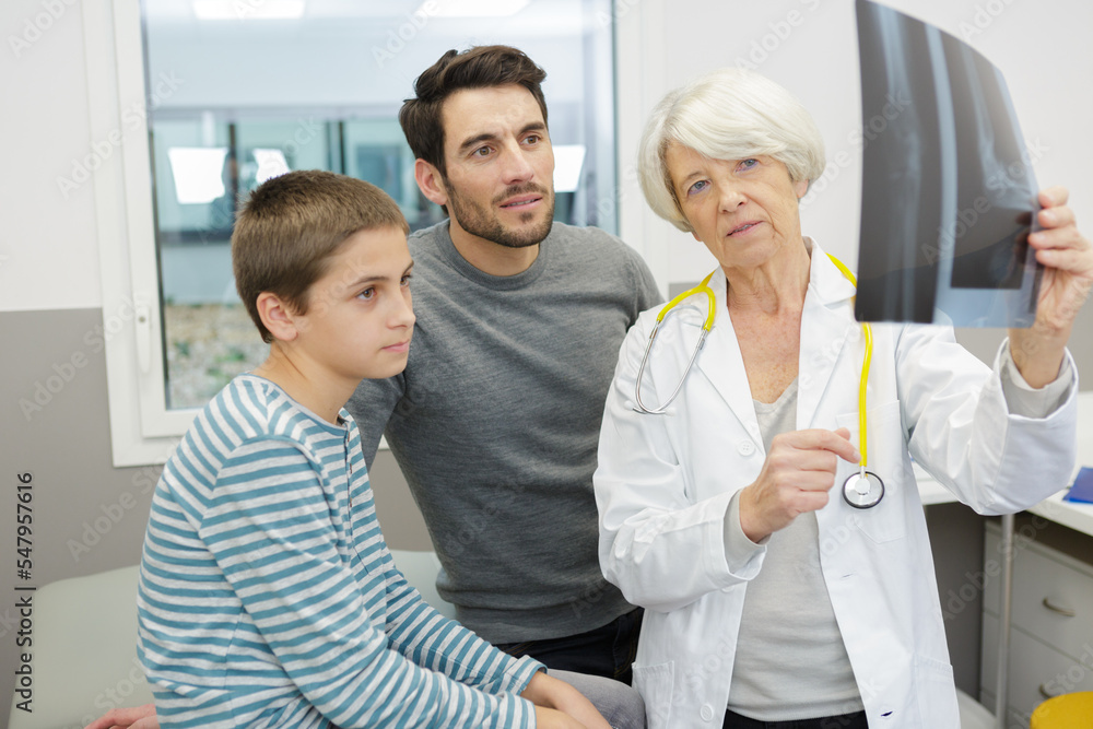 senior doctor showing xray to boy and dad senior doctor showing xray to boy and dad