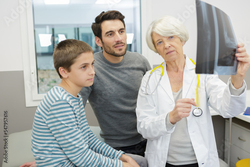 senior doctor showing xray to boy and dad