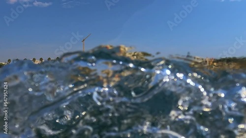 Unusual scene of Santa Maria di Leuca south Italian coast and cityscape saw from sailing boat moving along Ionian coast of Salento in Apulia, Italy. Low-angle water surface pov photo