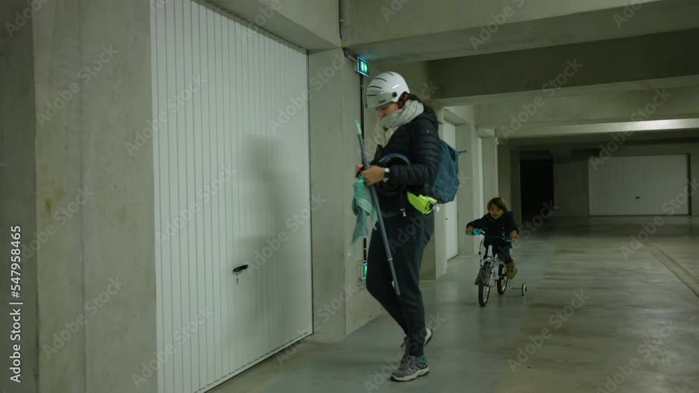 Mother opening underground garage with child riding bike. Parent and kid preparing for weekend activity Mother opening underground garage with child riding bike. Parent and kid preparing for weekend activity